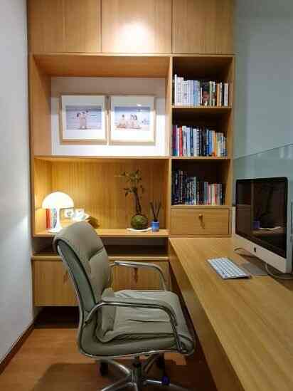 A small, simple home office with white walls and wood-tone furniture designed for remote work