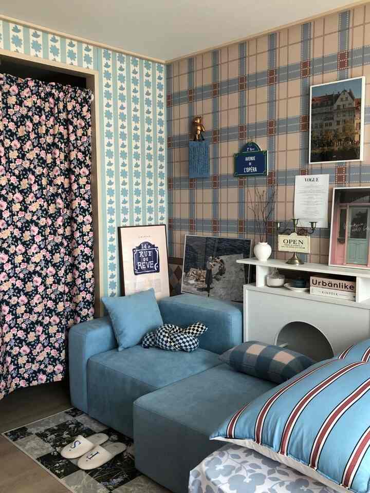 ネイビーブルーの花柄カーテンとブルーのソファが配置された、ヴィンテージ感のある寝室のインテリア