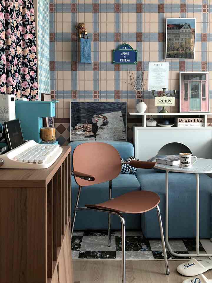 Living room with a brown armchair and blue sofa against checked wallpaper, featuring a cozy vintage atmosphere