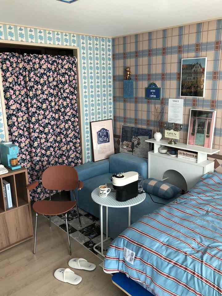 Blue and brown toned bedroom featuring striped bedding, blue sofa, and coffee machine creating a cozy atmosphere