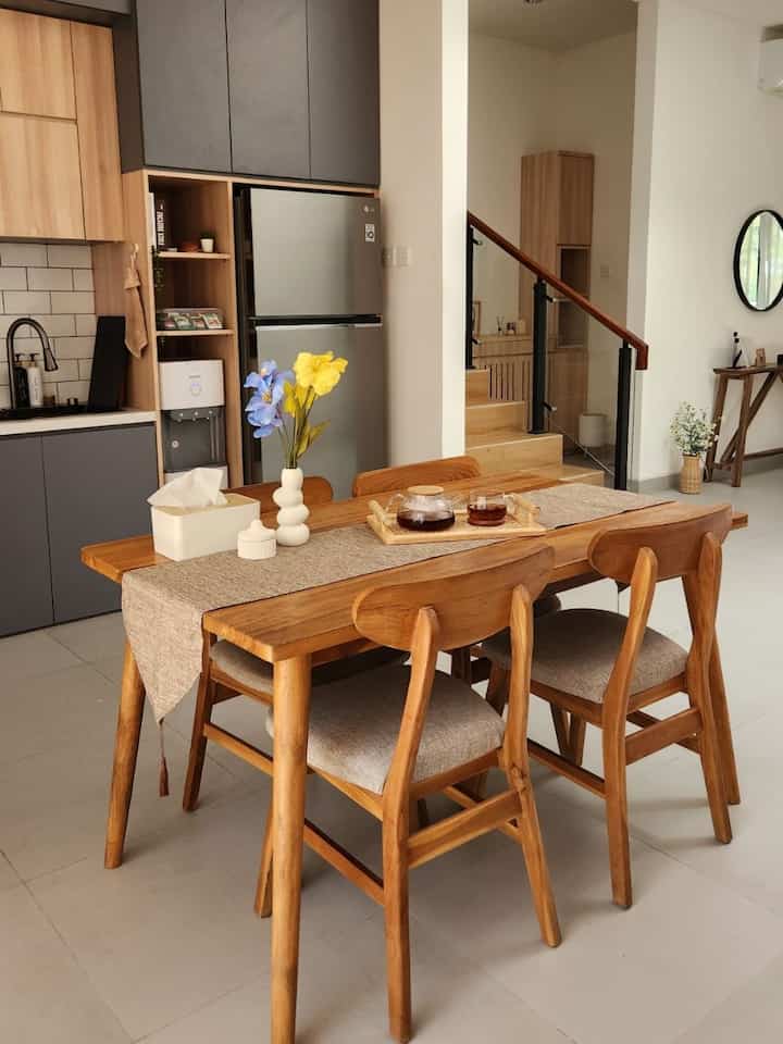 Wood tone and white dining room featuring wooden dining table and chairs with a vase, creating a cozy atmosphere