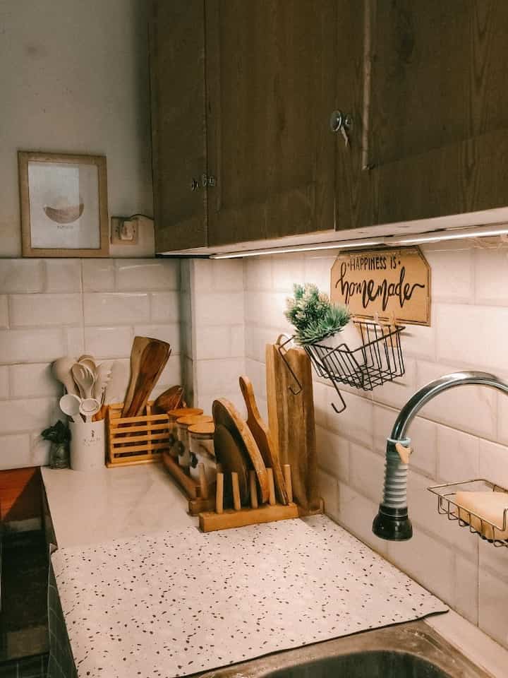 Natural toned kitchen space featuring white tiled backsplash, wooden cabinets and cutting boards in a minimal style