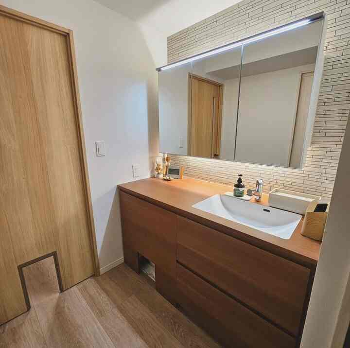 Natural modern bathroom featuring wood tone cabinetry, white tiled backsplash, and built-in cat door for pet access
