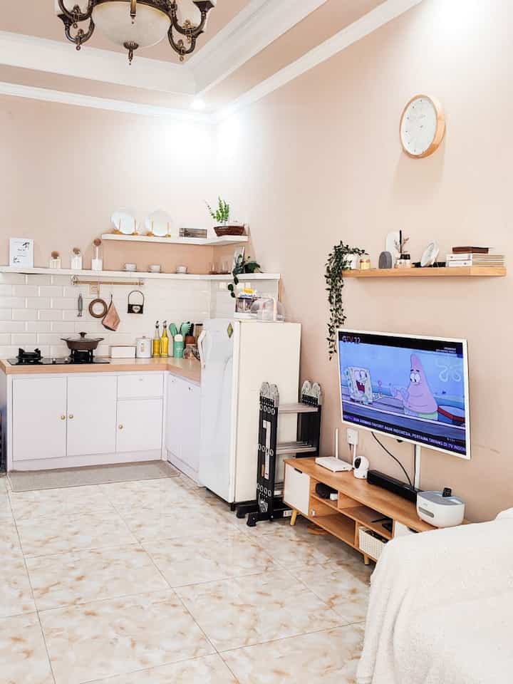White and beige toned compact studio apartment combining kitchen and living area with simple and clean design