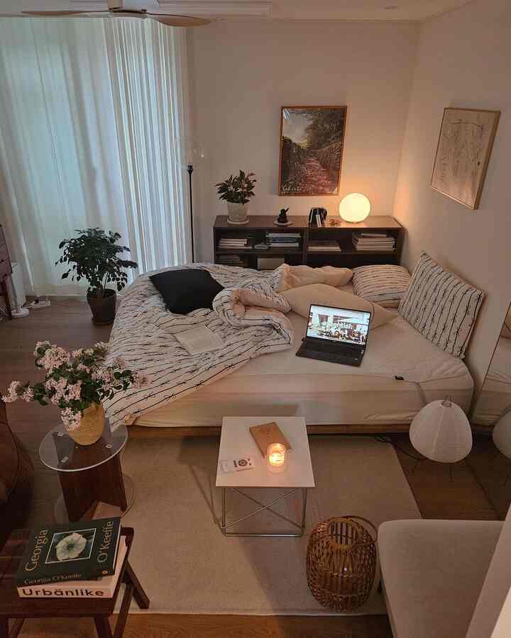 White and brown toned bedroom featuring cozy bed, mood lighting, and plants creating a warm natural atmosphere