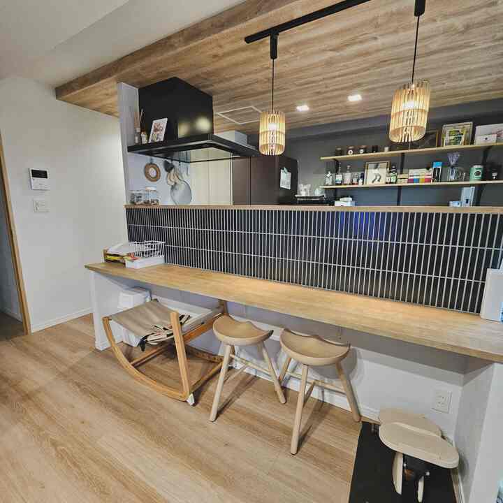 Wood tone and black tile kitchen counter space featuring stools, a cat item, and a children's rocking chair for a cozy kitchen interior