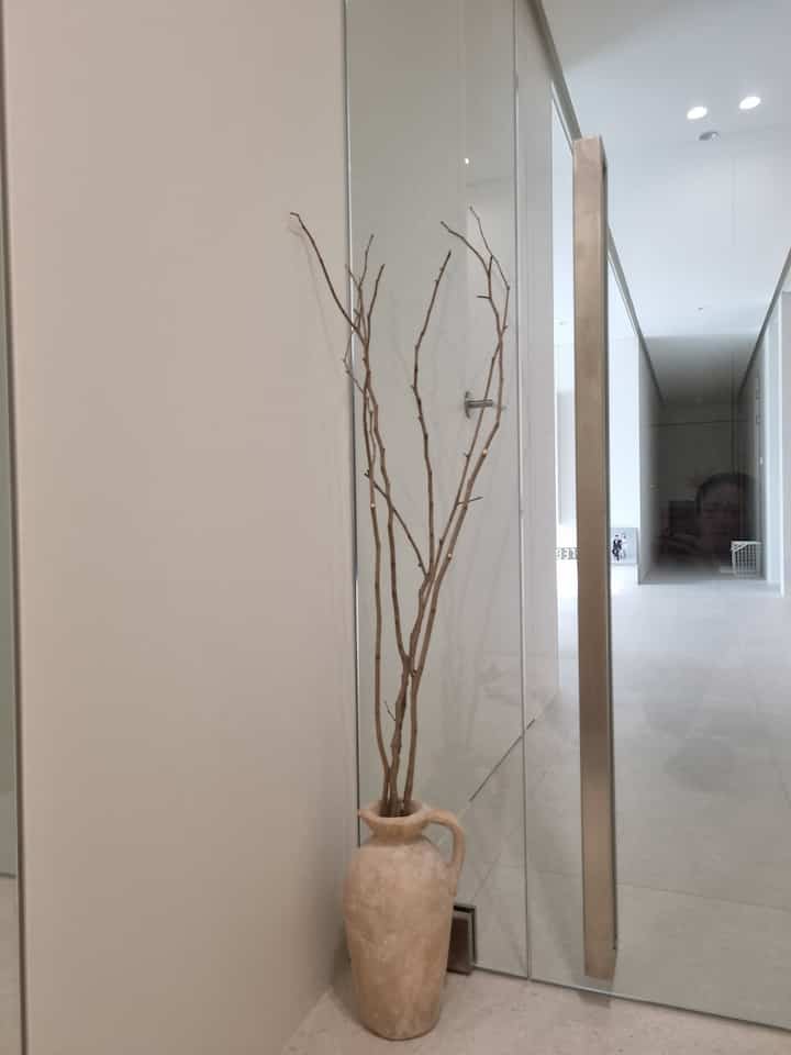 ブラウン系のテラコッタの花瓶と枝が置かれたモダンな玄関、シンプルでナチュラルな雰囲気のインテリア