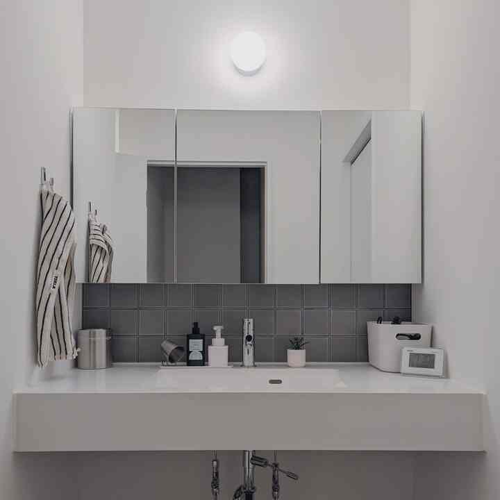 ホワイトとグレーのトーンのミニマルな洗面台と鏡が配置された清潔感のある浴室