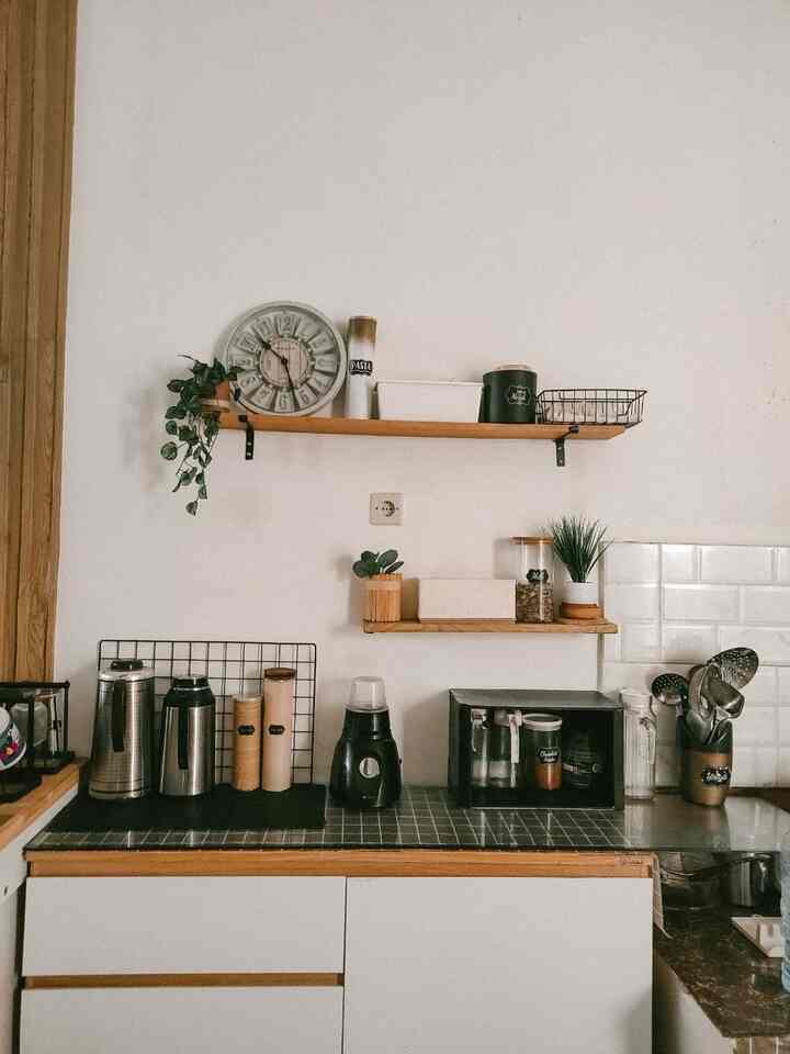 Natural-toned kitchen with white walls and wooden shelves, featuring neatly arranged kitchen appliances and utensils for a minimalist aesthetic
