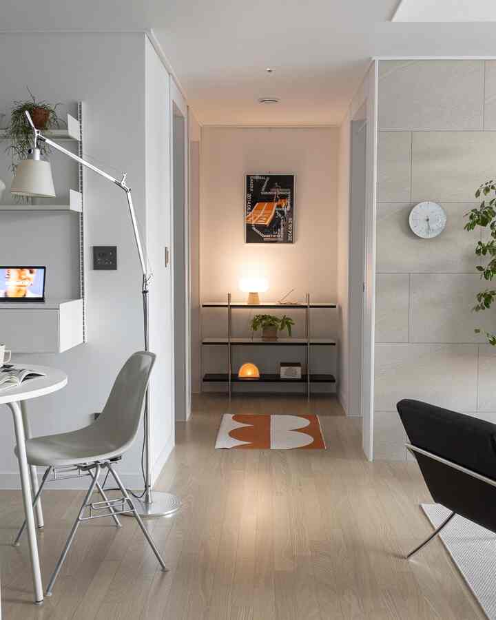 Minimal hallway in white and wood tones featuring a 3-tier shelf, lamps, and a decorative rug creating a cozy atmosphere