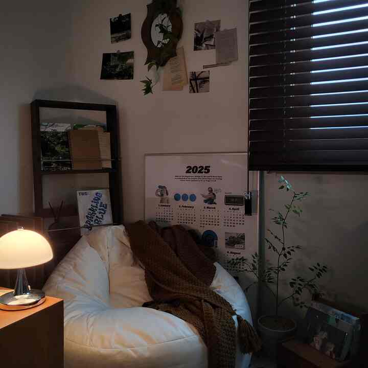 White and brown toned living room featuring a comfortable bean bag sofa, soft lighting, and a plant creating a cozy atmosphere