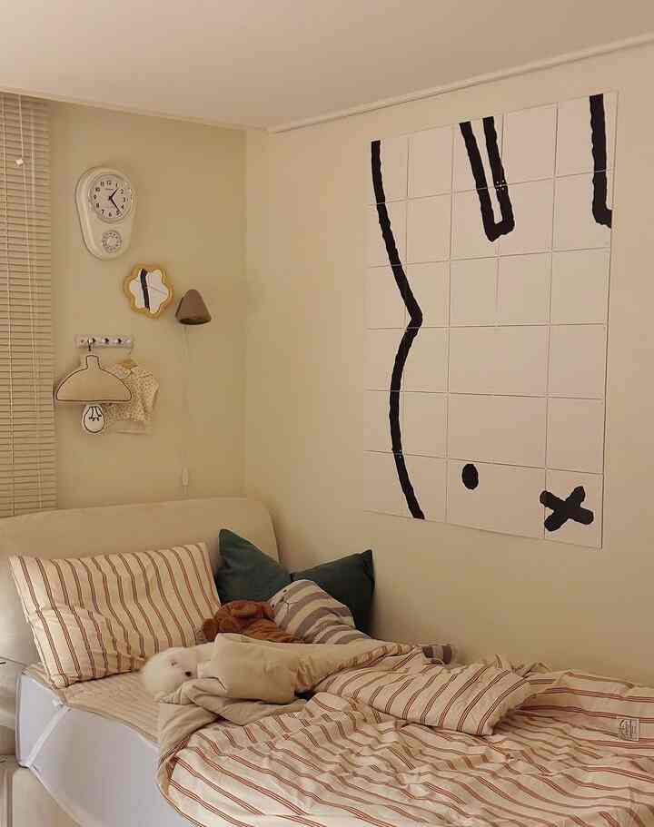 White and beige toned kids' room featuring Miffy modular wall art and a dog on the bed, creating a cozy atmosphere
