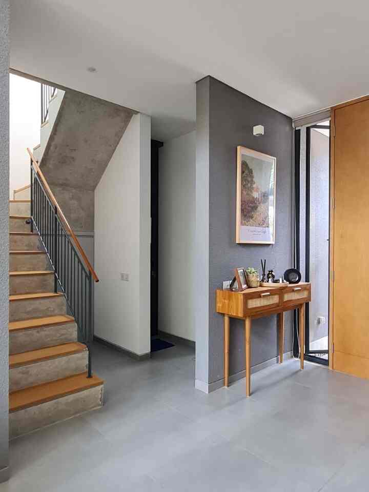 Modern entrance with gray and wood tones, featuring a console table and stairs in a clean, minimalist space