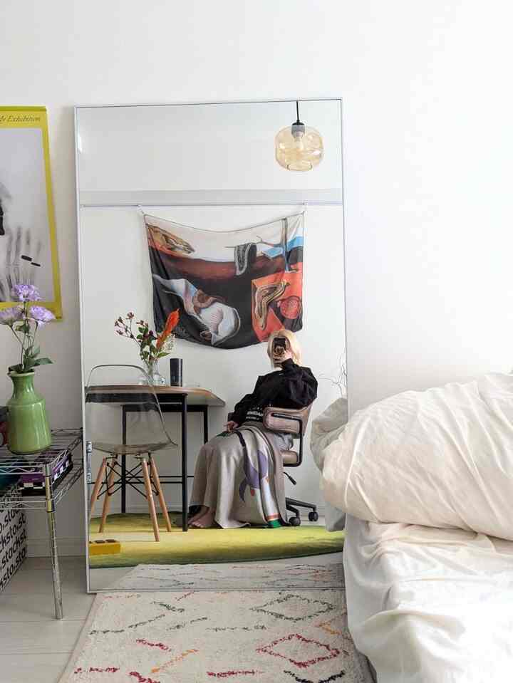 落ち着いたブラウンとナチュラルなトーンのワークスペース、広い全身鏡とパターン付きラグがあるシンプルなインテリア