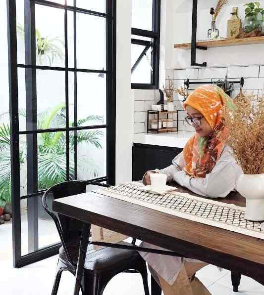 Bright white and black wood-toned dining room featuring dining table and chairs, plants, and vase creating a cafe-style atmosphere
