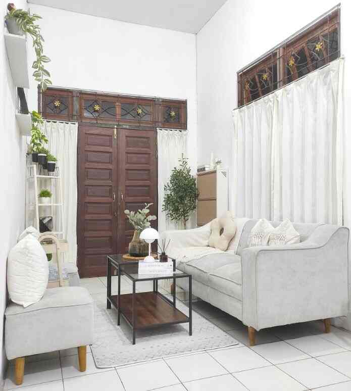 White-toned simple living room featuring gray sofa, coffee table, and plants with a cozy, clean atmosphere