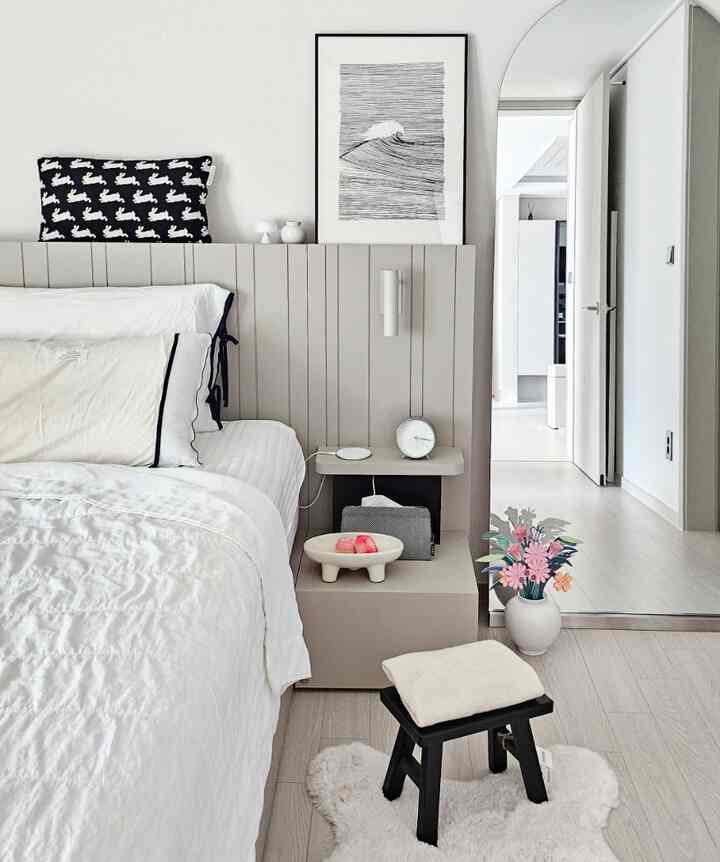 White and gray toned bedroom featuring a simple modern style with bed, nightstand, and stool arranged neatly