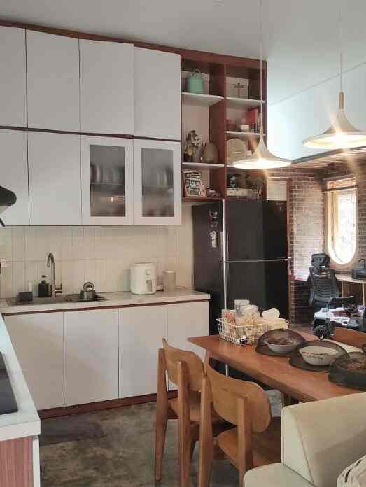 Modern kitchen with white cabinetry and natural wood dining table, featuring pendant lights and a cozy, stylish atmosphere