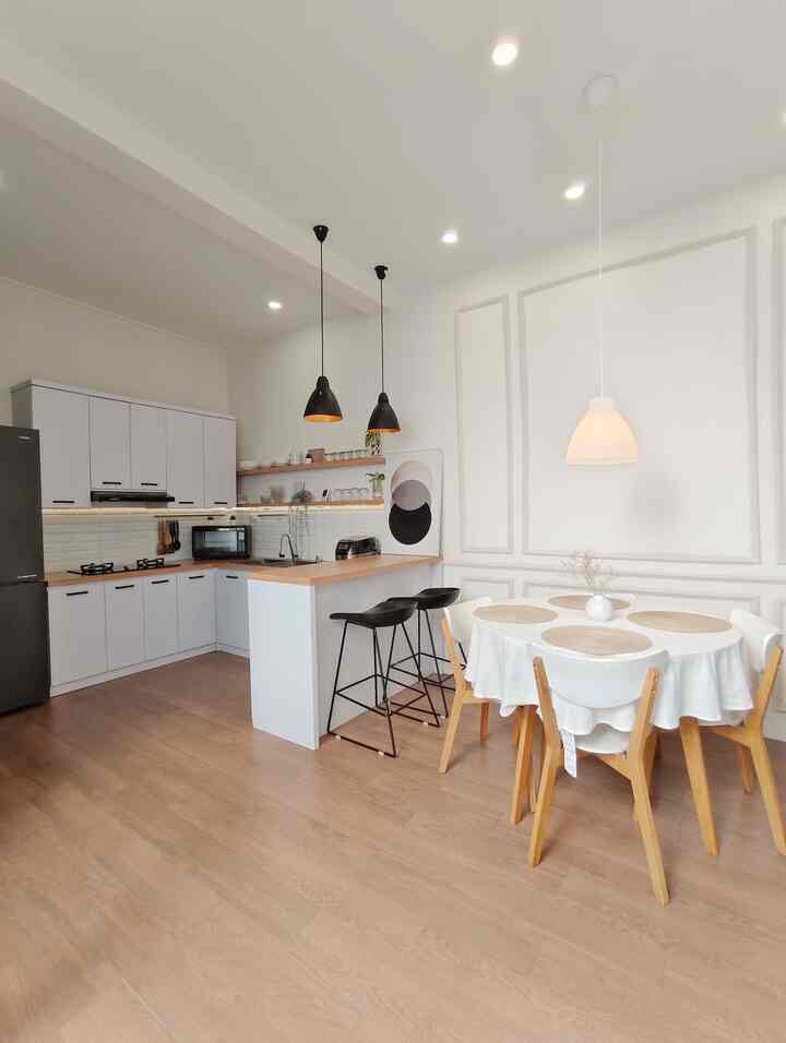 White and wood tone kitchen and dining room featuring a round dining table and pendant lights in a clean, cozy space