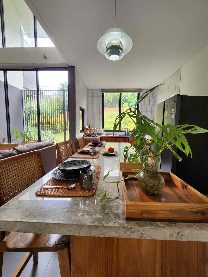 Natural wood tones and white walls blend in this dining room featuring a table and chairs creating a cozy open atmosphere