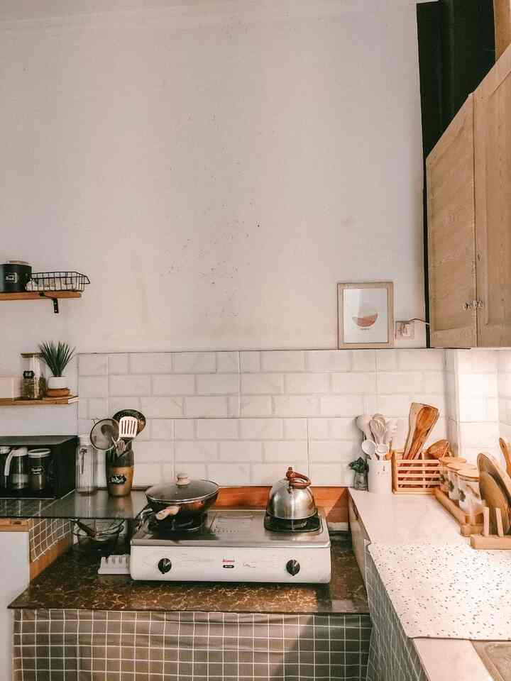 Natural and white tone kitchen featuring wooden utensils and gas stove, arranged in a clean and simple setting