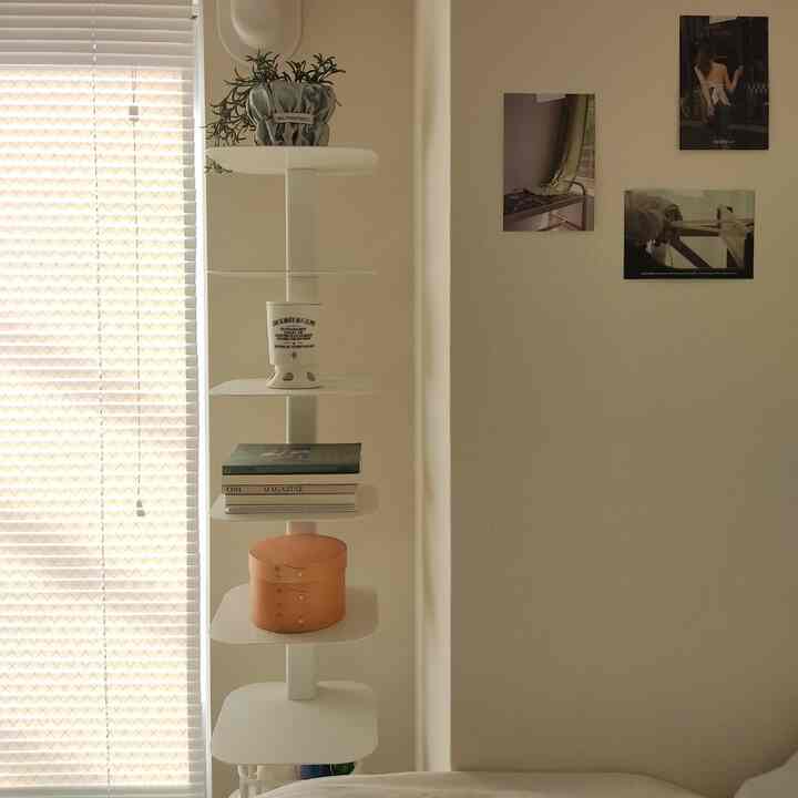 白を基調とした寝室に北欧風の白い棚と小さな装飾品が配置された雰囲気のあるインテリア