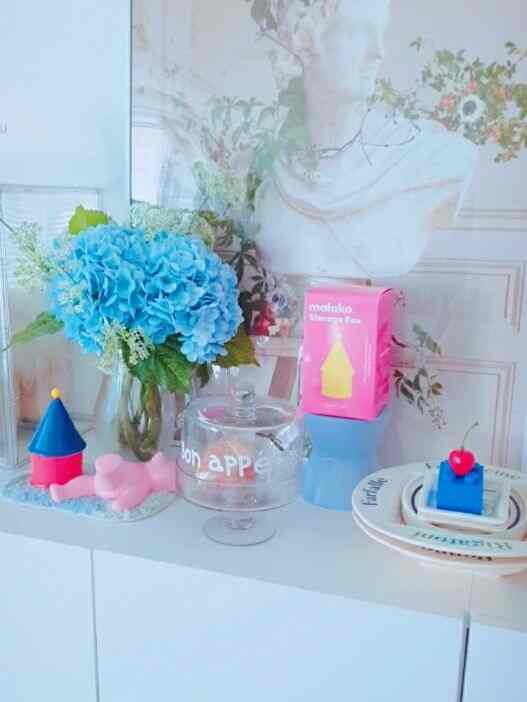 ホワイトの収納キャビネットの上に青い紫陽花と装飾的なオブジェが配置されたフレンチカントリースタイルのインテリア