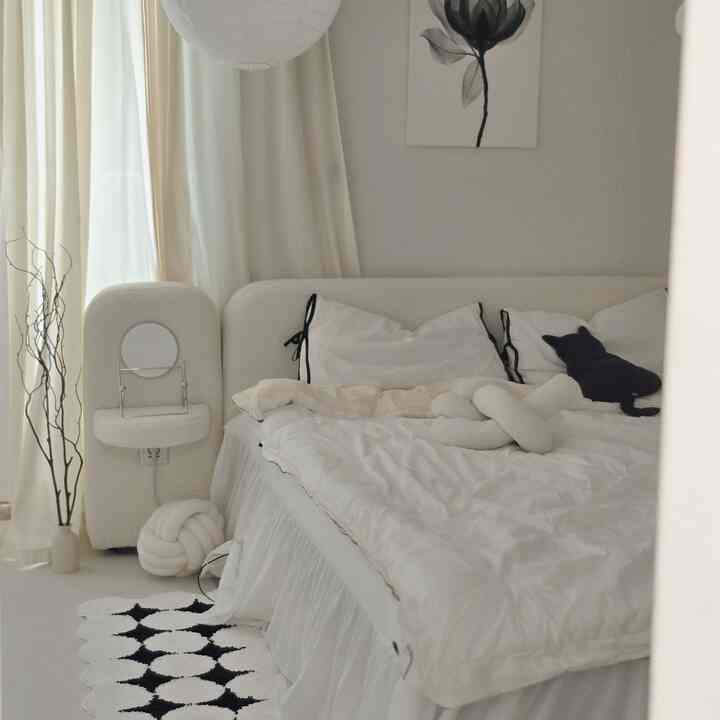 White-toned bedroom featuring a fabric bed and cream-colored curtains with a simple, cozy atmosphere