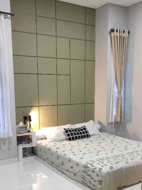 Simple designed bedroom with green padded wall and beige curtains, featuring a large bed centered with a small nightstand