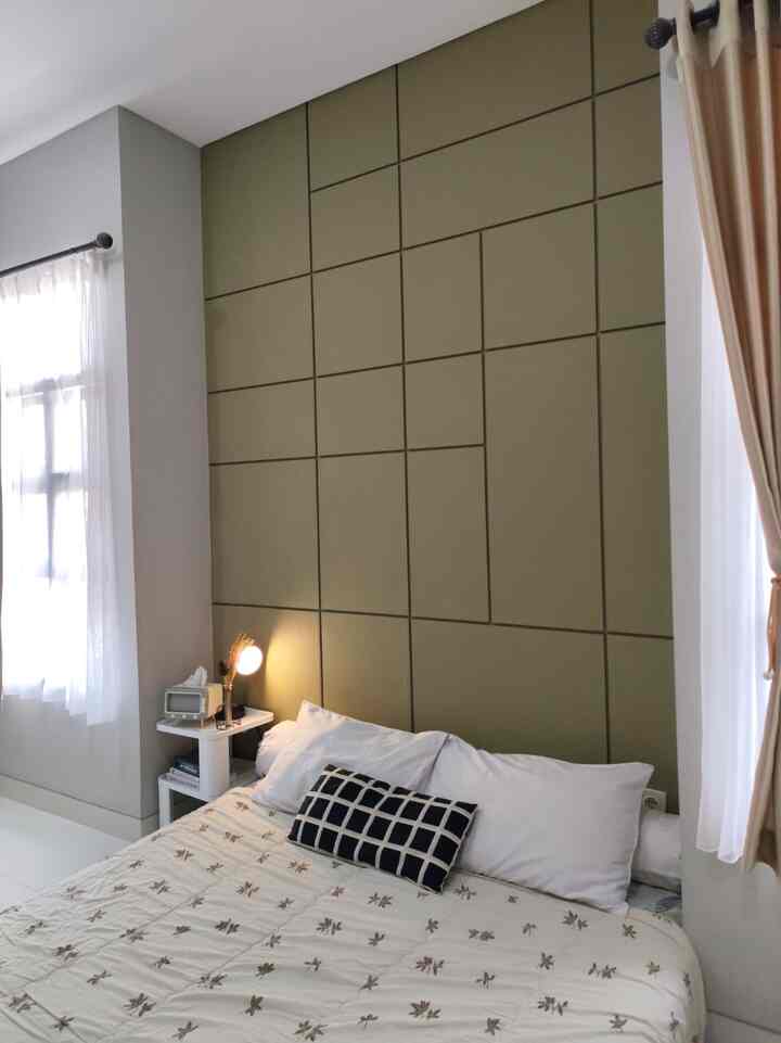 Natural-toned bedroom featuring olive green paneled wall, white bedding, and a nightstand creating a cozy atmosphere