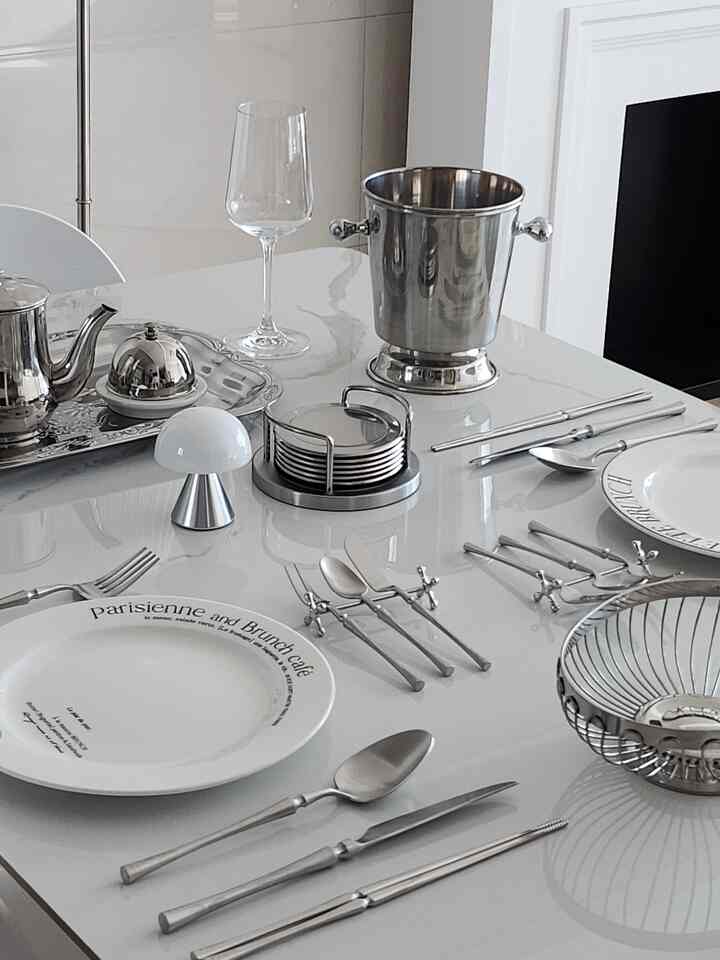 White and silver-toned dining room featuring a ceramic dining table and modern fireplace with clean and elegant atmosphere