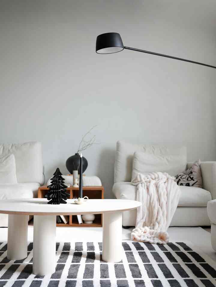 Modern living room in white and black tones featuring simple sofas, a round coffee table, and a floor lamp