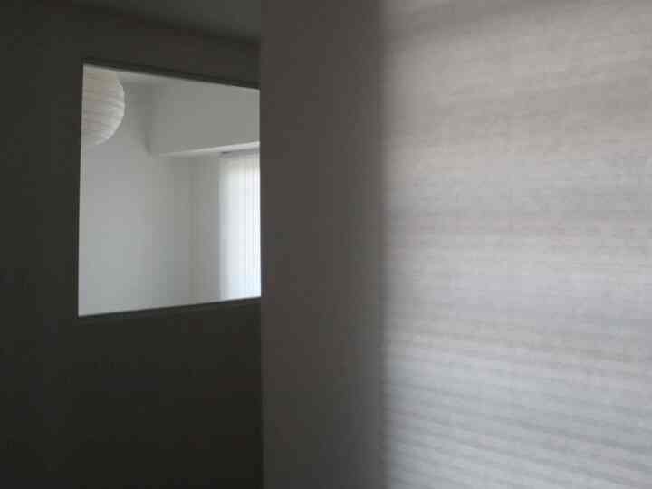 Bright white-toned entrance featuring a window view into a simple and modern bedroom