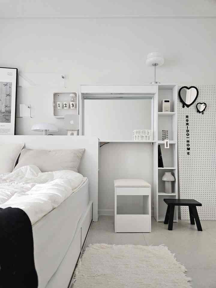 ホワイトトーンのコンパクトな部屋にベッドと化粧台が配置されたミニマルなインテリア