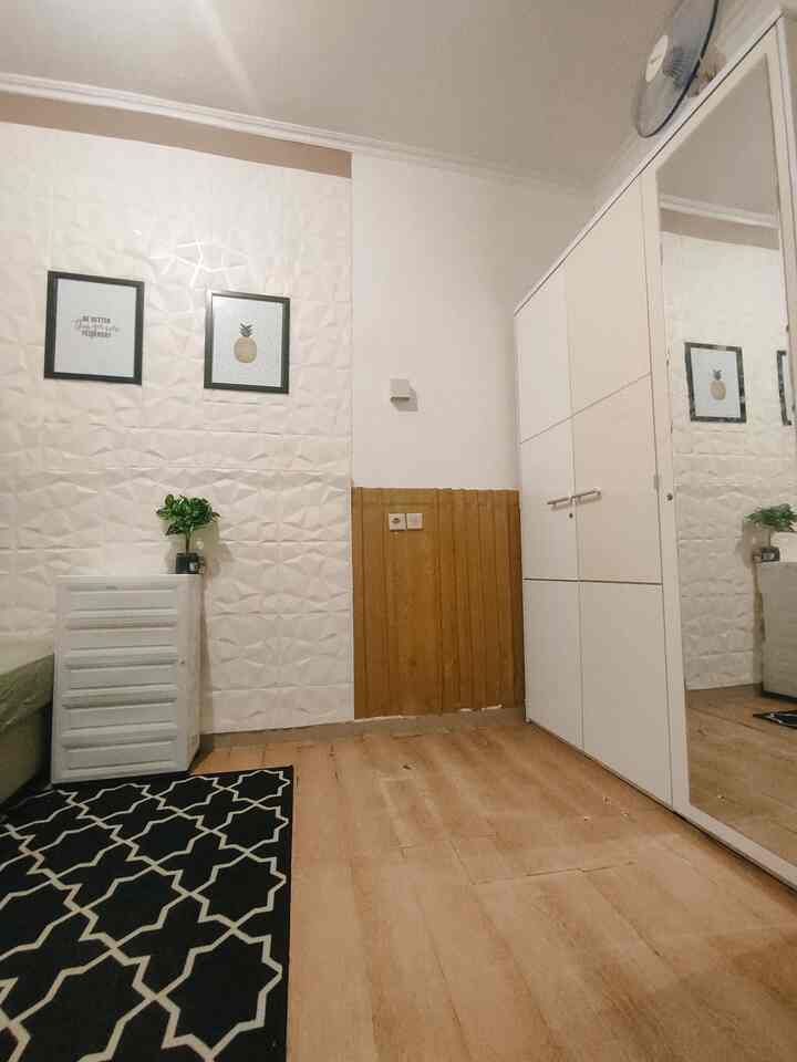 Minimal bedroom with white and wood tones, featuring a white wardrobe and patterned carpet creating a sense of spaciousness