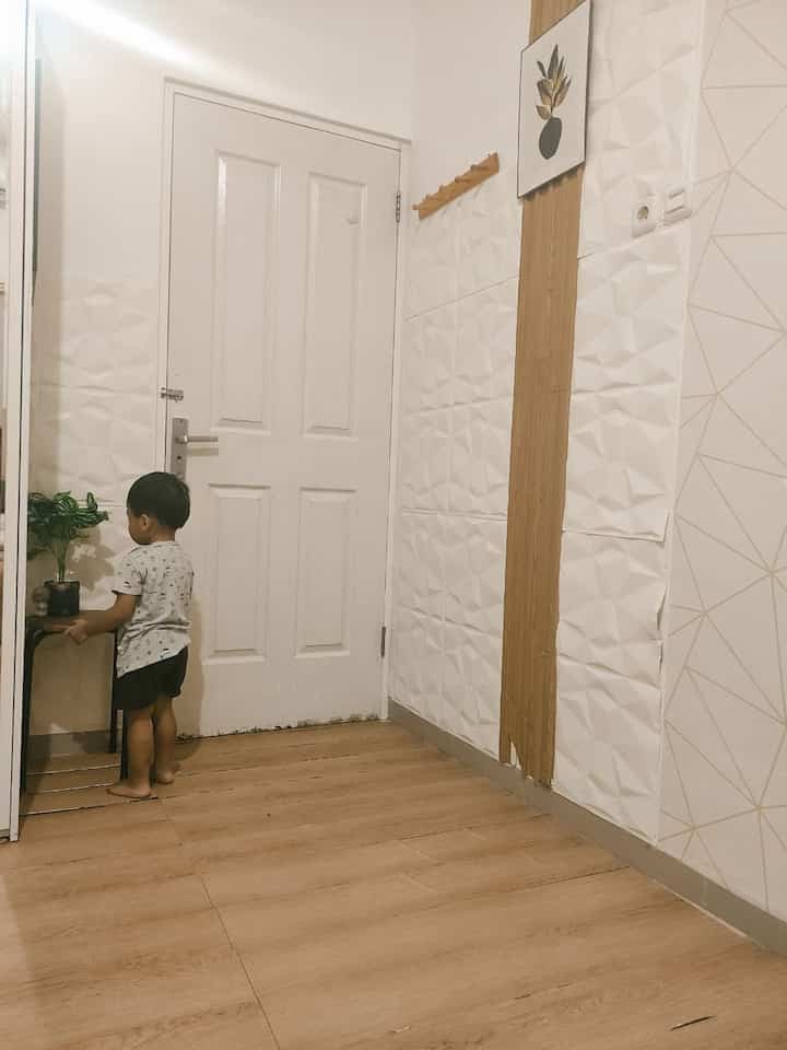 White and wood tone entrance space featuring a child and a plant table, creating a warm atmosphere