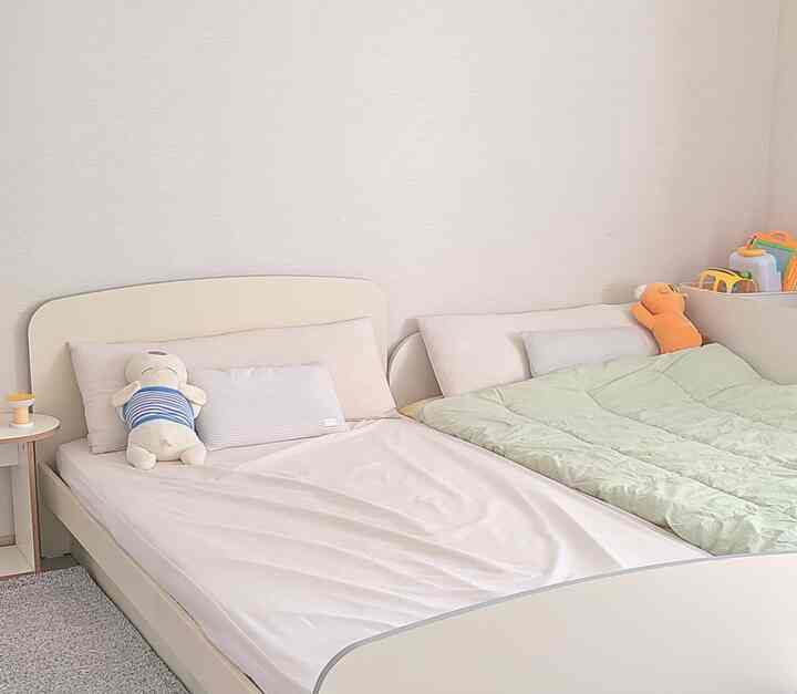 ベージュ調の子供部屋、二つのベッドとぬいぐるみが配置されたシンプルでナチュラルな雰囲気のインテリア