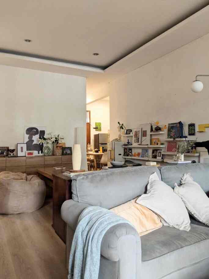 In my house, the open space area is the living room area that is integrated with the living room. Actually, because we rarely receive guests, our living room also functions as a living room, so the living room in the middle is used as a multifunctional area. Because there are 4 dogs in the house, this middle area has more decorations on the walls so that the middle area of the floor can be used as a doggy play space. In this room, I use a table and bean bags that can be moved as needed. This table can be stored on a storage box near the wall when we need floor space, then it can be pulled to the middle when we need a table to work or eat. There is no built-in furniture in this area because I want this area to be able to be changed quickly as needed. This room is dominated by various materials and wood colors for furniture, inspired by mid-century design. And I provide a gallery wall to display home decorations such as artwork, books, or favorite figurines to give a personal and eclectic impression 
#Credenza #MidCenturyFurniture #ArtWall #Frame #ArtPrint #BeanBag #lampumeja #RumahOpenSpace #RumahTanpaSekat