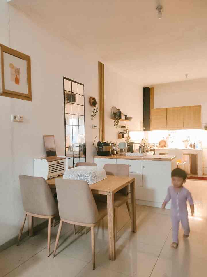 Bright white and wood-toned kitchen with a 4-person dining table in a cozy compact dining area featuring a child in motion