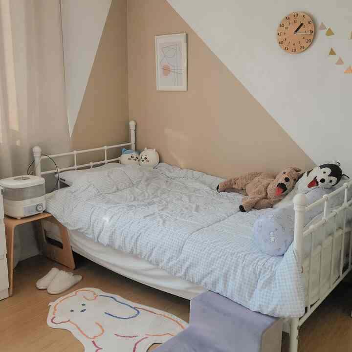 ベージュとホワイトの色調の小さな寝室、白いベッドフレームとかわいい犬のぬいぐるみが配置された居心地の良い空間