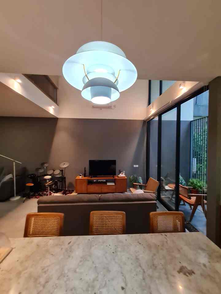 Natural-colored living room featuring wood tone furniture, pendant light, and large windows in a modern setting