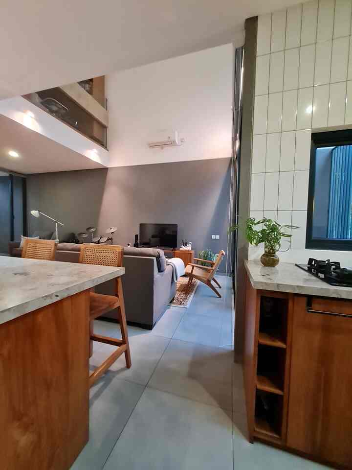 Open-plan living and kitchen space in gray and brown tones, featuring modern and natural elements with a spacious, bright atmosphere