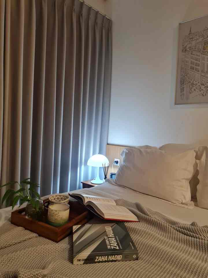Monotone bedroom with white walls, gray curtains, wooden nightstand and bedding creating a simple natural space