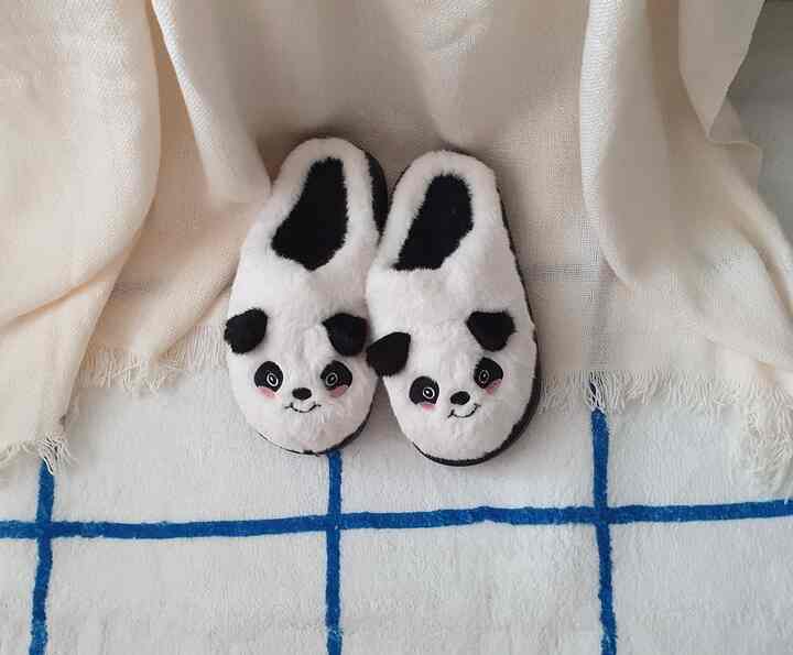 白いラグとクリーム色のブランケットの上にかわいいパンダのスリッパが置かれた居心地の良いリビング空間