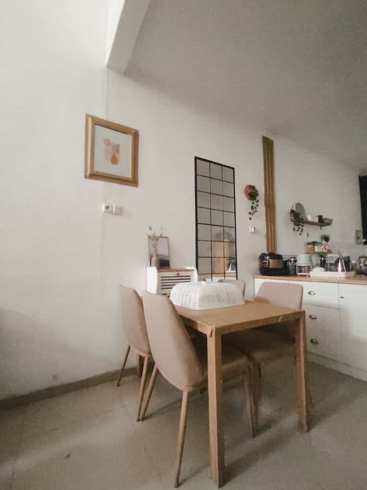 Natural tone cozy small kitchen-dining area with white walls and beige dining chairs arranged around wooden table