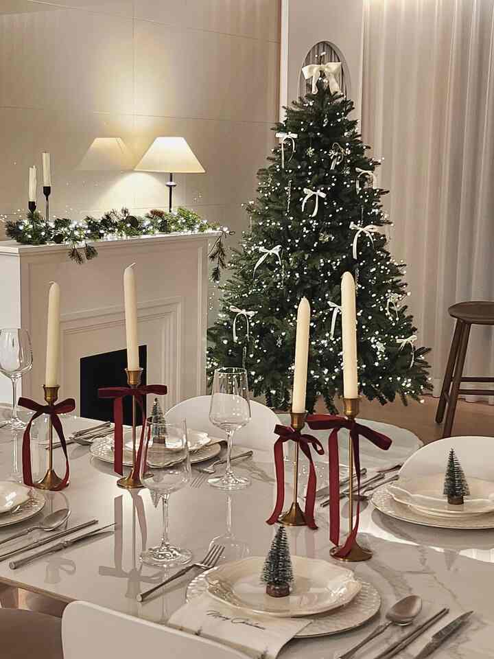 White and red toned dining room featuring a Christmas tree and candles set on a festive home party table with cozy atmosphere