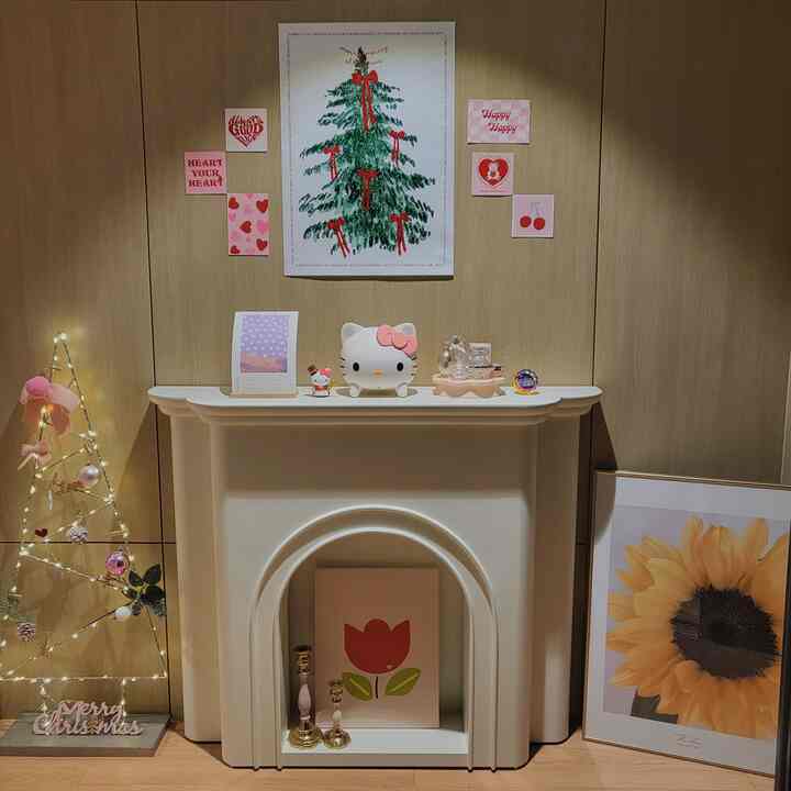 Cozy interior featuring wood tones and pink accents with decorative fireplace lamp and wall posters