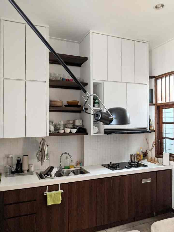 Berhubung dapur itu isinya 90% furniture built in, kadang buat bikin dapur terasa cozy dan hidup itu agak tricky. Furniture built in terutama yang berukuran besar seringkali bikin ruangan terasa kayak hotel atau showroom dan menurutku jadi terasa kaku🤣. Nah karena barang keluargaku banyak banget, mau gak mau harus banyak sekali kabinet built in yang tinggi di dapur ini. 
Untuk mengimbangi agar terasa lebih cozy dan hidup, aku menggunakan lukisan atau art print agar memberikan personality ke dapur. Baru-baru ini aku menambahkan frame untuk memajang lukisan di ambalan dapur. Ambalan yang biasa diisi perlengkapan dapur jadi terlihat lebih styled dengan adanya lukisan di antara perlengkapan dapur. Kebetulan di dapur tidak bisa menaruh tanaman hidup karena kurang cahaya matahari, jadi aku memberikan aksen warna hijau untuk memberikan kesan nature. Selain itu, aku menggunakan basket anyaman handmade untuk menambah nuansa hidup di dapur supaya dapur tidak terlalu kaku. Basket ini selain untuk dekorasi bisa digunakan untuk storage supaya dapur lebih rapih✨
#KitchenSet #KitchenSetMinimalis #DapurEclectic #Backplash #ArtPrint #ArtFrame #MyDreamKitchen #KitchenRenovation #KitchenStyling