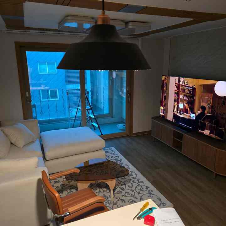 白と茶色のトーンのリビング、ソファとテレビ台が配置された落ち着いた雰囲気の空間