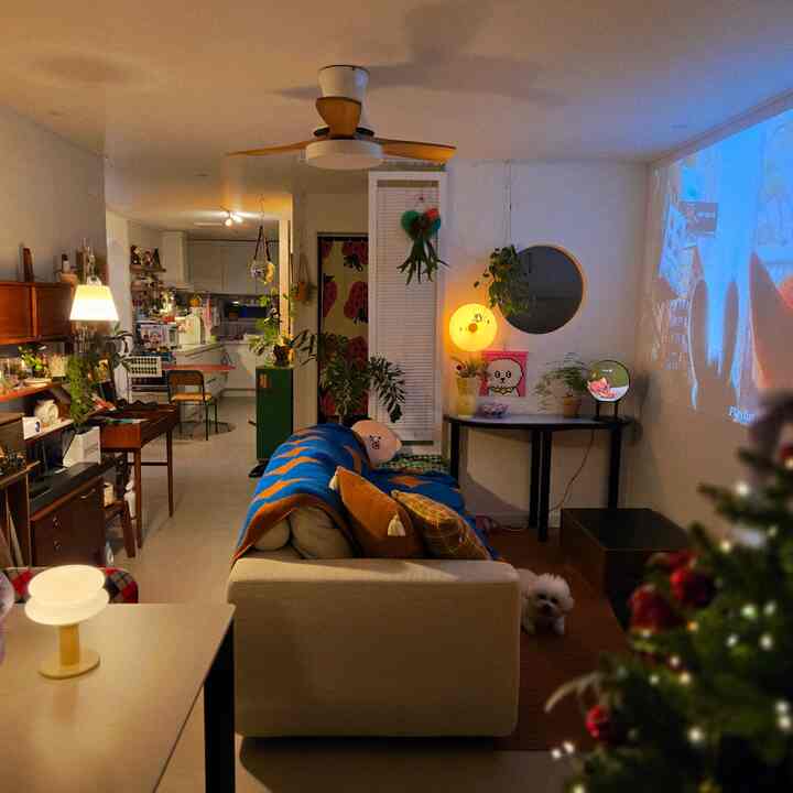 ベージュとナチュラルトーンのリビング、ソファとブラインド、植物、ムード照明が安らぎの空間を演出している